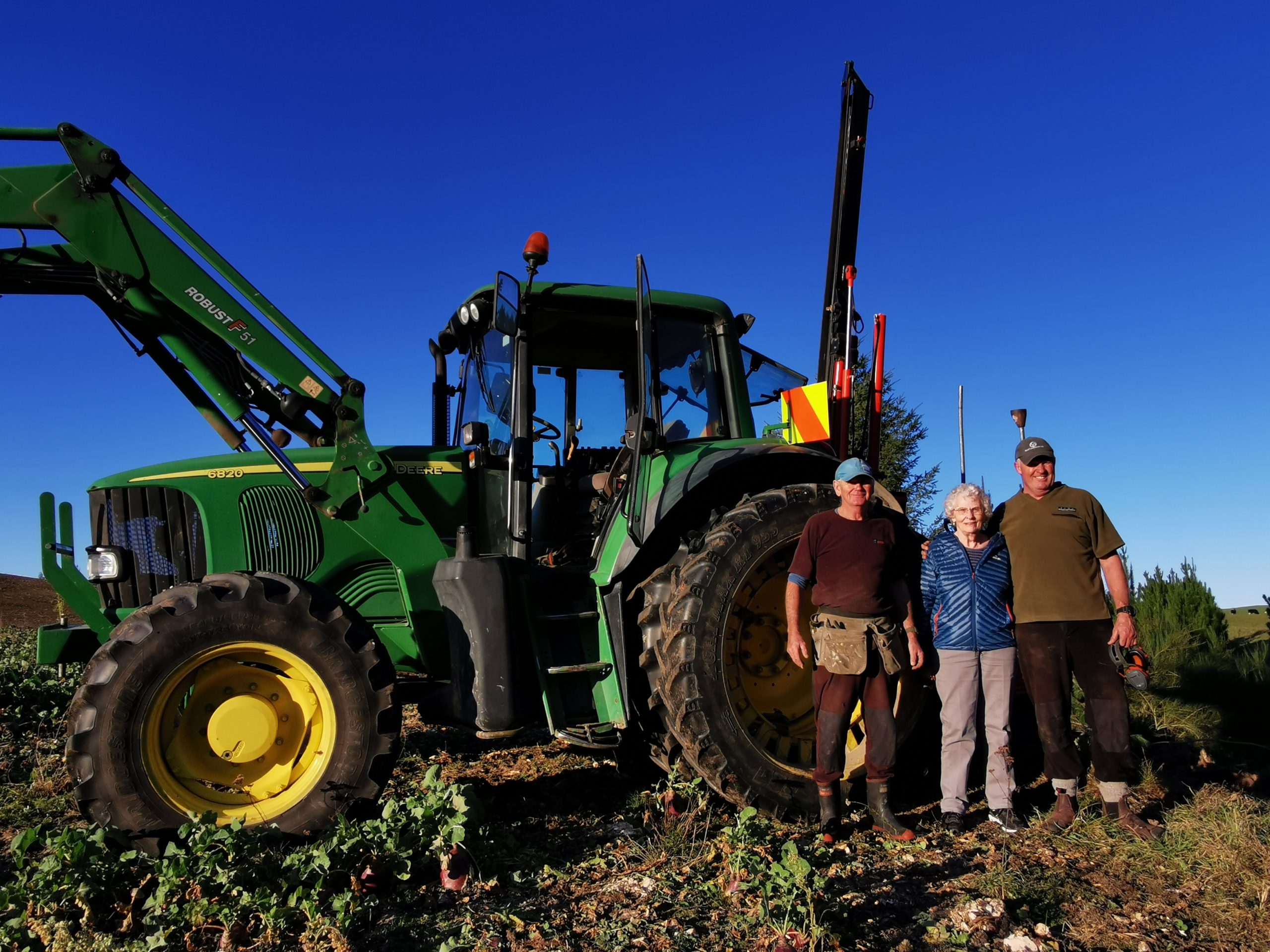 three people standing in front of a tractor.