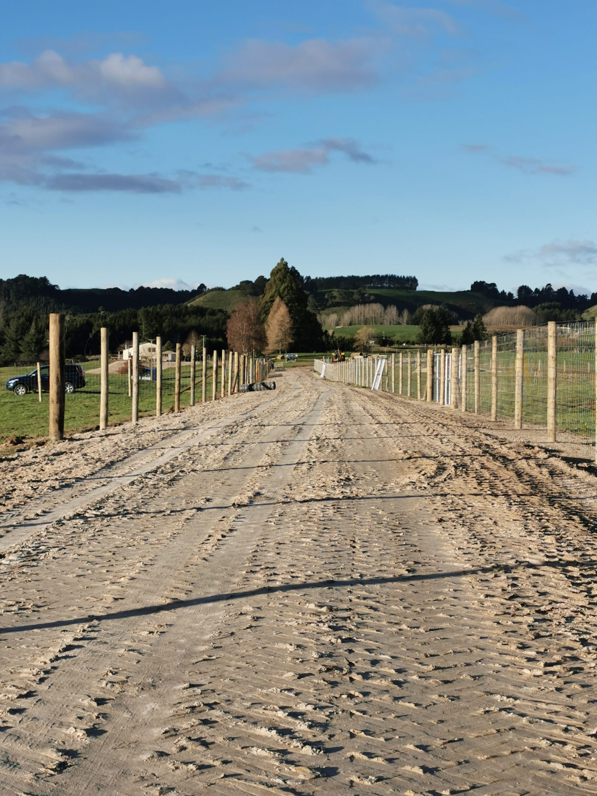 a dirt road with a wooden fence on the side.