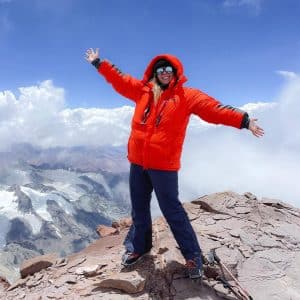a woman standing on top of a mountain with her arms outstretched.